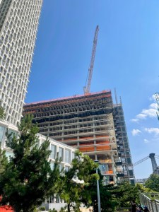 A high-rise building under construction with a tower crane against a blue sky