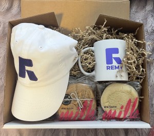 A Remy gift box with a white cap featuring the purple R logo, a Remy mug and cookies